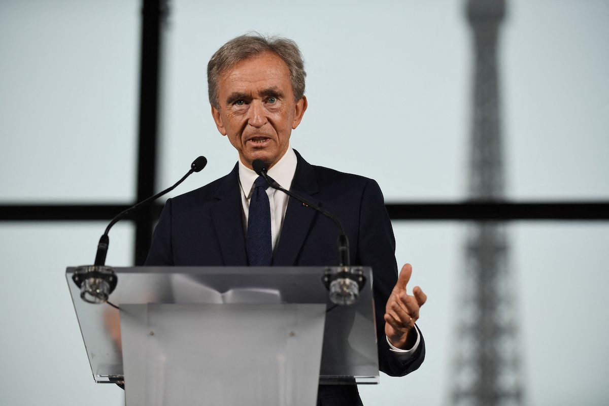 A man standing at a podium with the Eiffel Tower behind him.