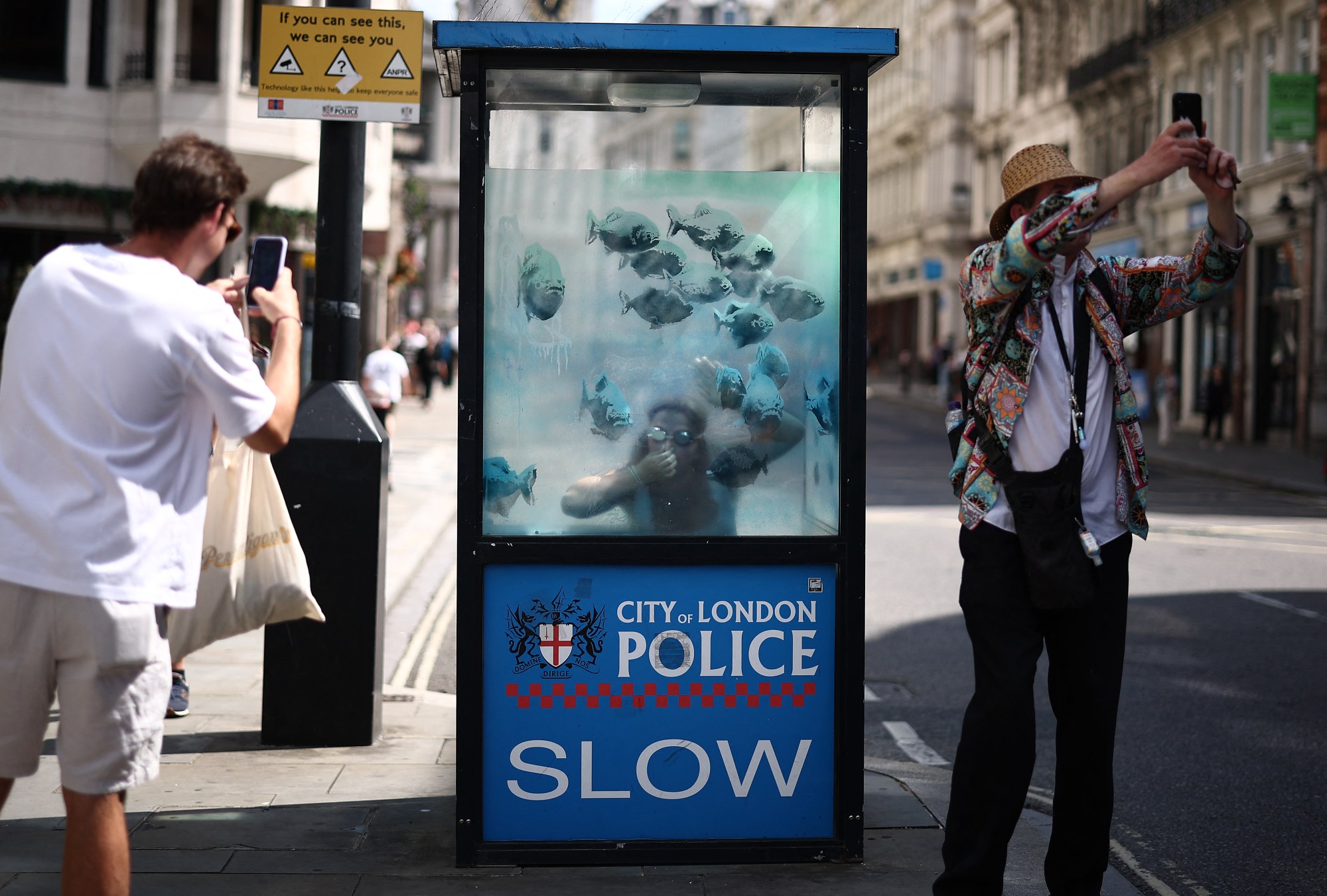 A police box painted with a fish mural.