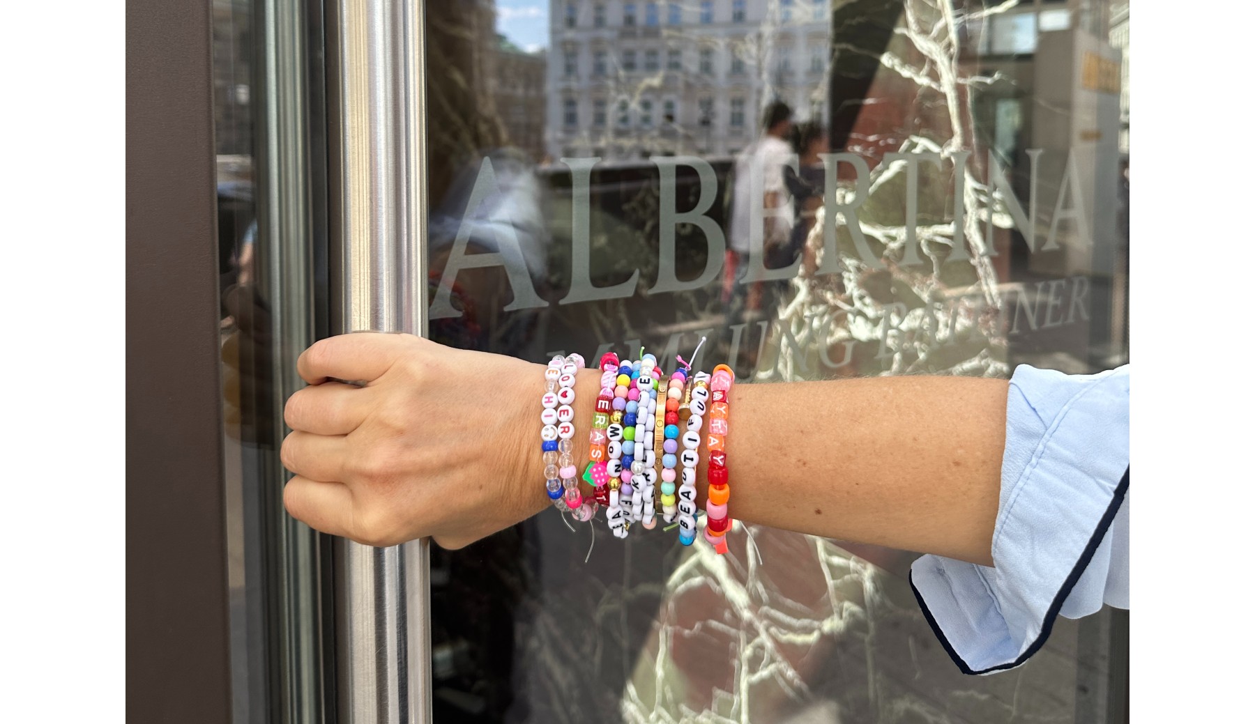 A Taylor Swift fan wearing multiple beaded bracelets holds the door of The Albertina museum in Vienna, Austria.