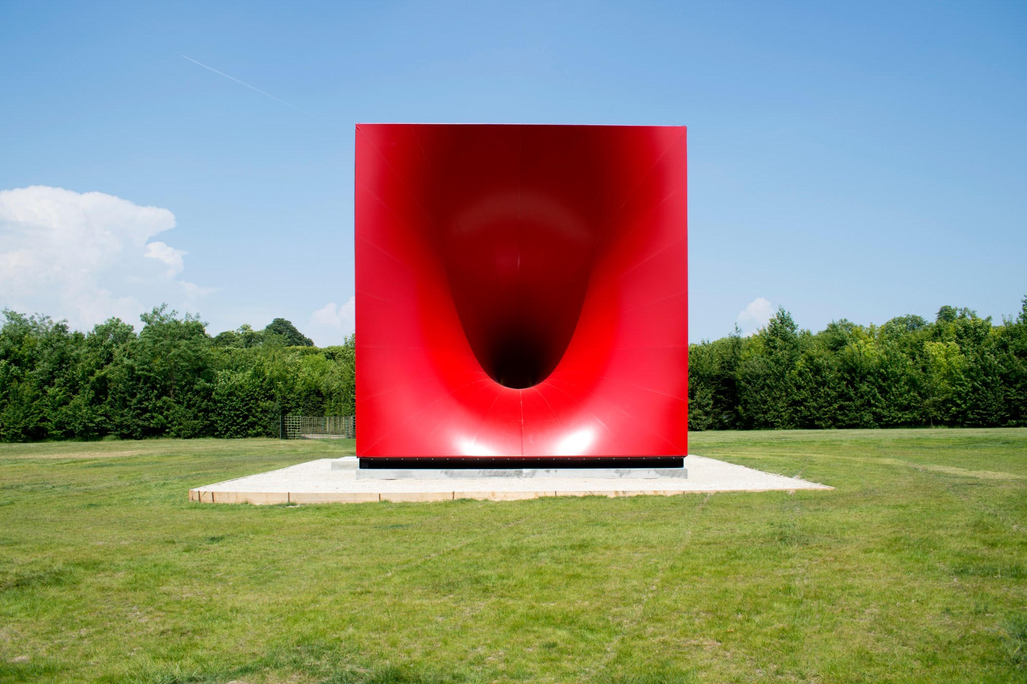 A red sculpture on a concrete plinth.