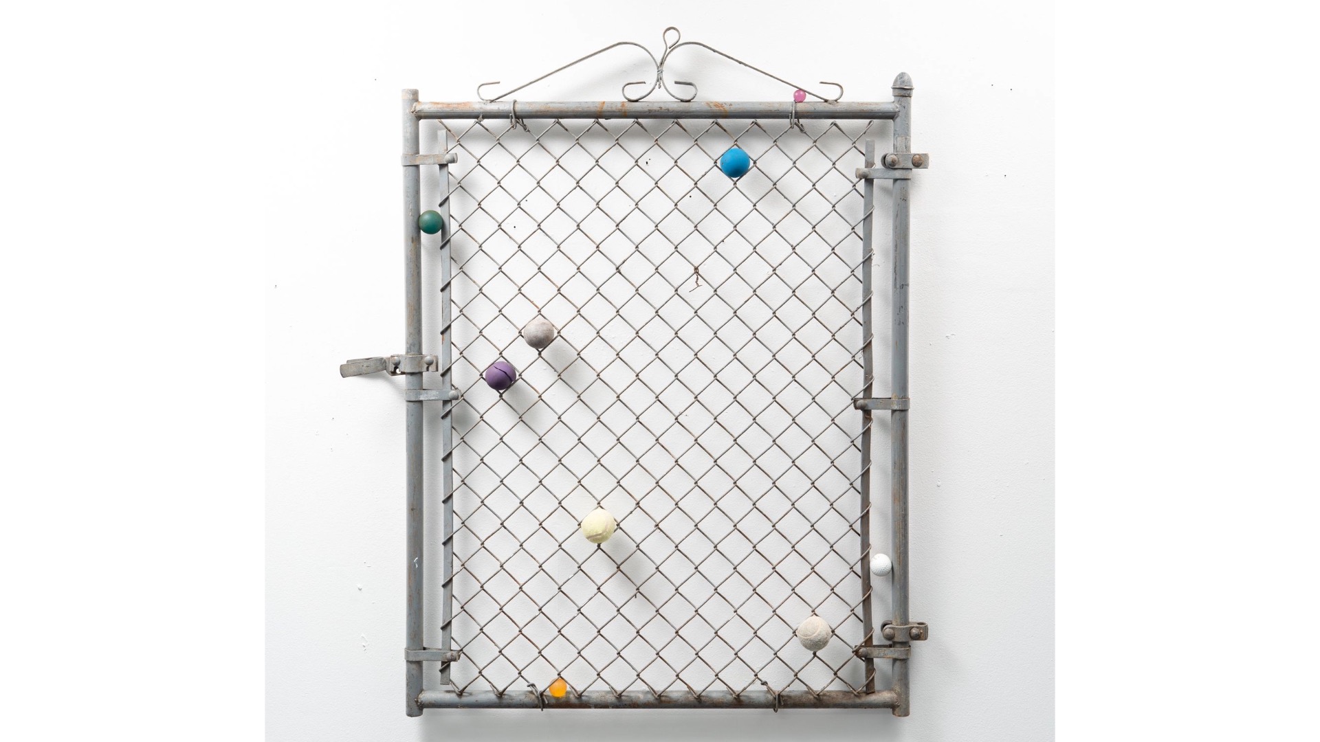 A sculpture by Eva Robarts comprised of a reclaimed chain-link gate and discarded tennis balls.